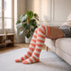 Chaussettes montantes rayées corail et blanc portées au-dessus du genou