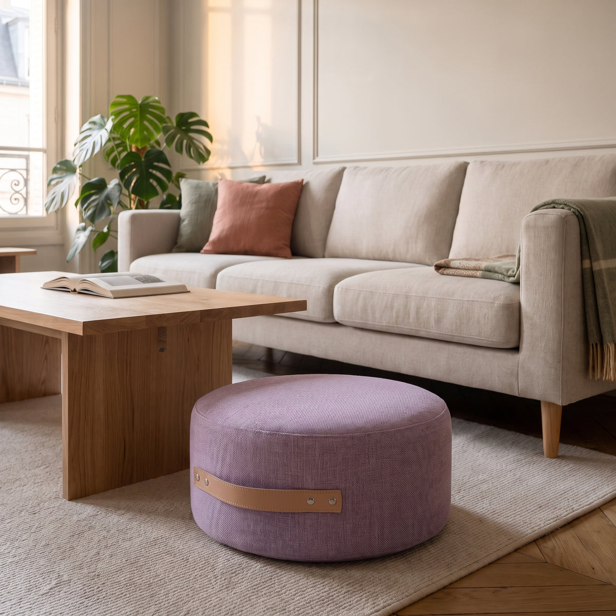 Pouf de sol rond parme posé sur le tapis du salon, poignée visible