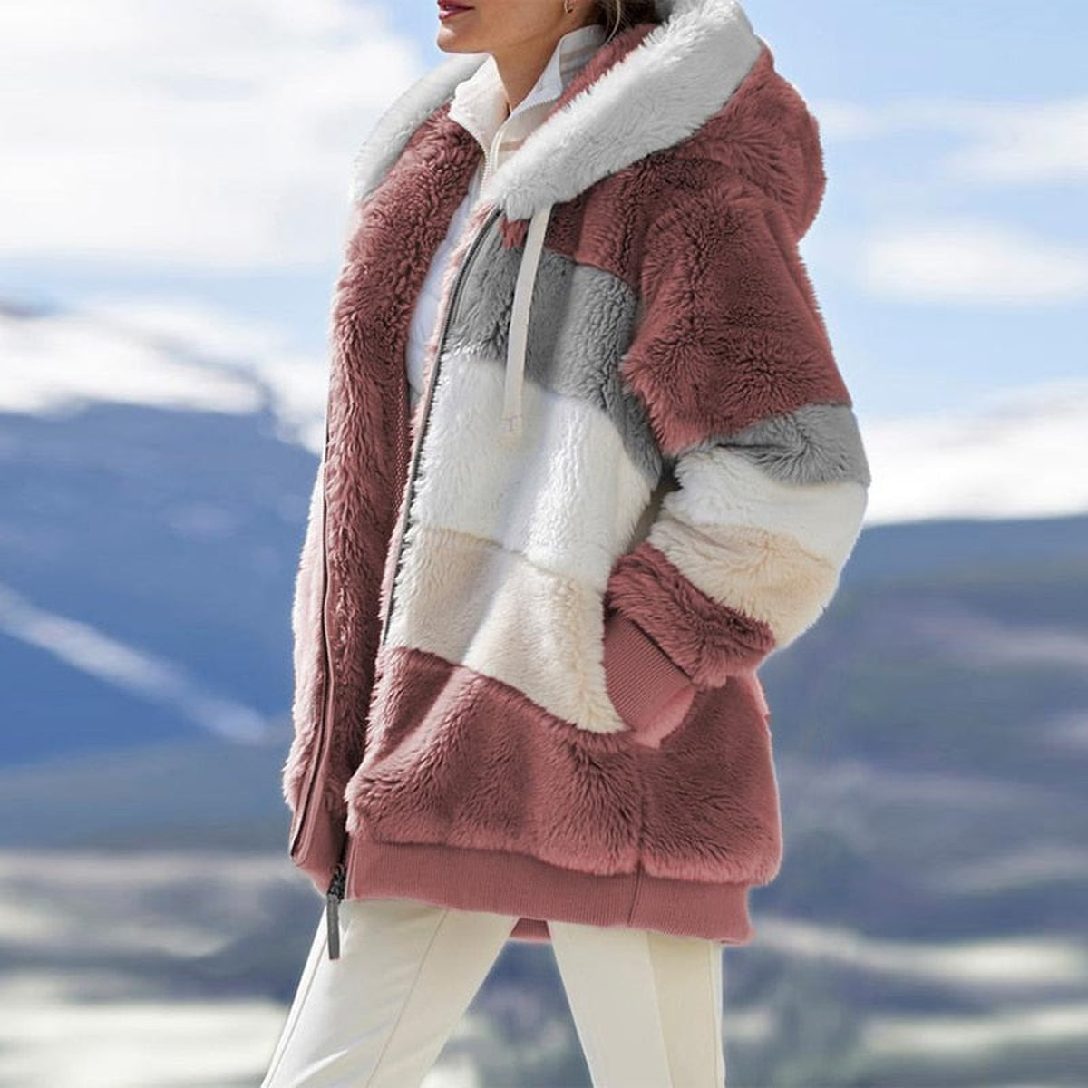 Veste rose en fausse fourrure vue en détail, capuche blanche et panneaux gris, blanc et crème