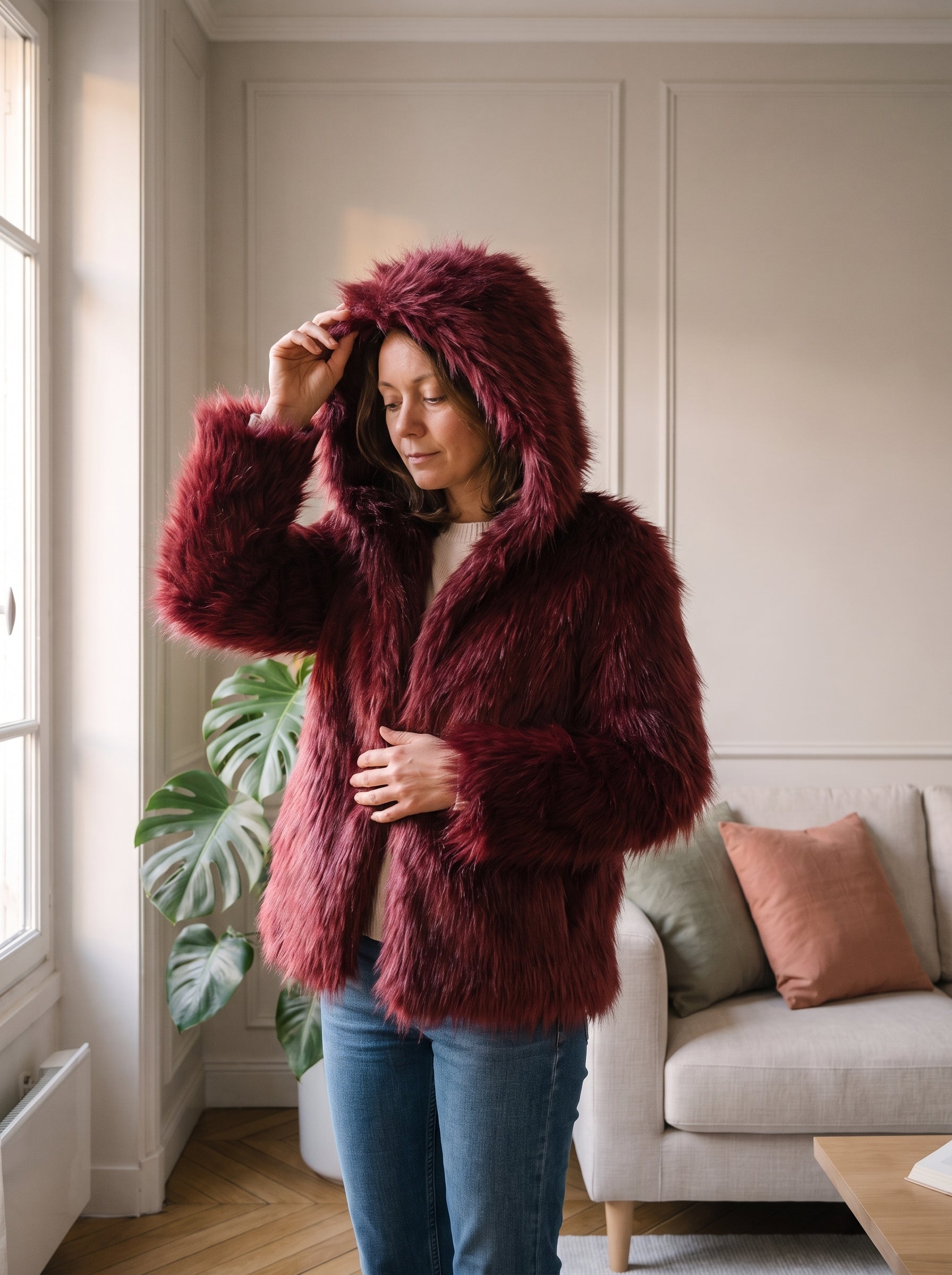 Femme du casting portant la veste rouge à capuche près de la fenêtre du salon Image