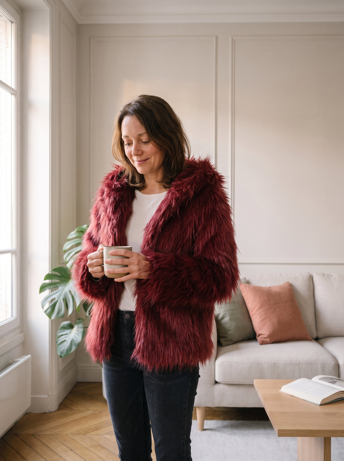 Femme du casting portant la veste à capuche poils longs rouge dans le salon