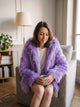 Femme du casting portant la veste à capuche poils longs violette dans le coin lecture