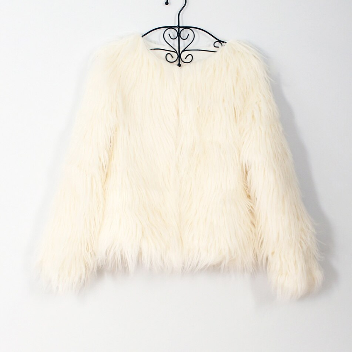 La veste creme sur son cintre, vue de face : la doublure ivoire apparait a l encolure et les rangees de poil se suivent jusqu a l ourlet