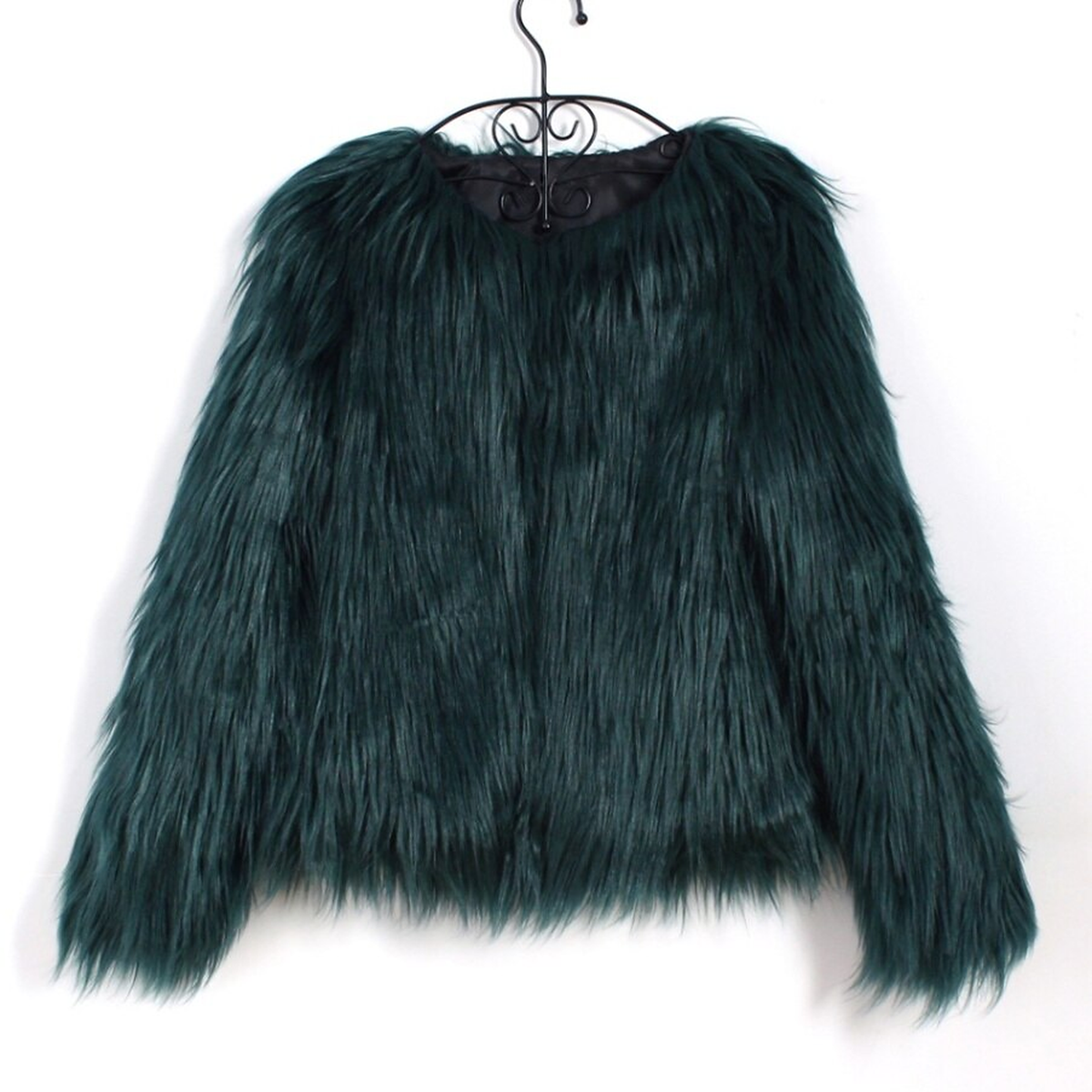 La veste vert sapin sur son cintre : le poil sombre absorbe la lumiere et les rangees se fondent, la doublure de l encolure est noire